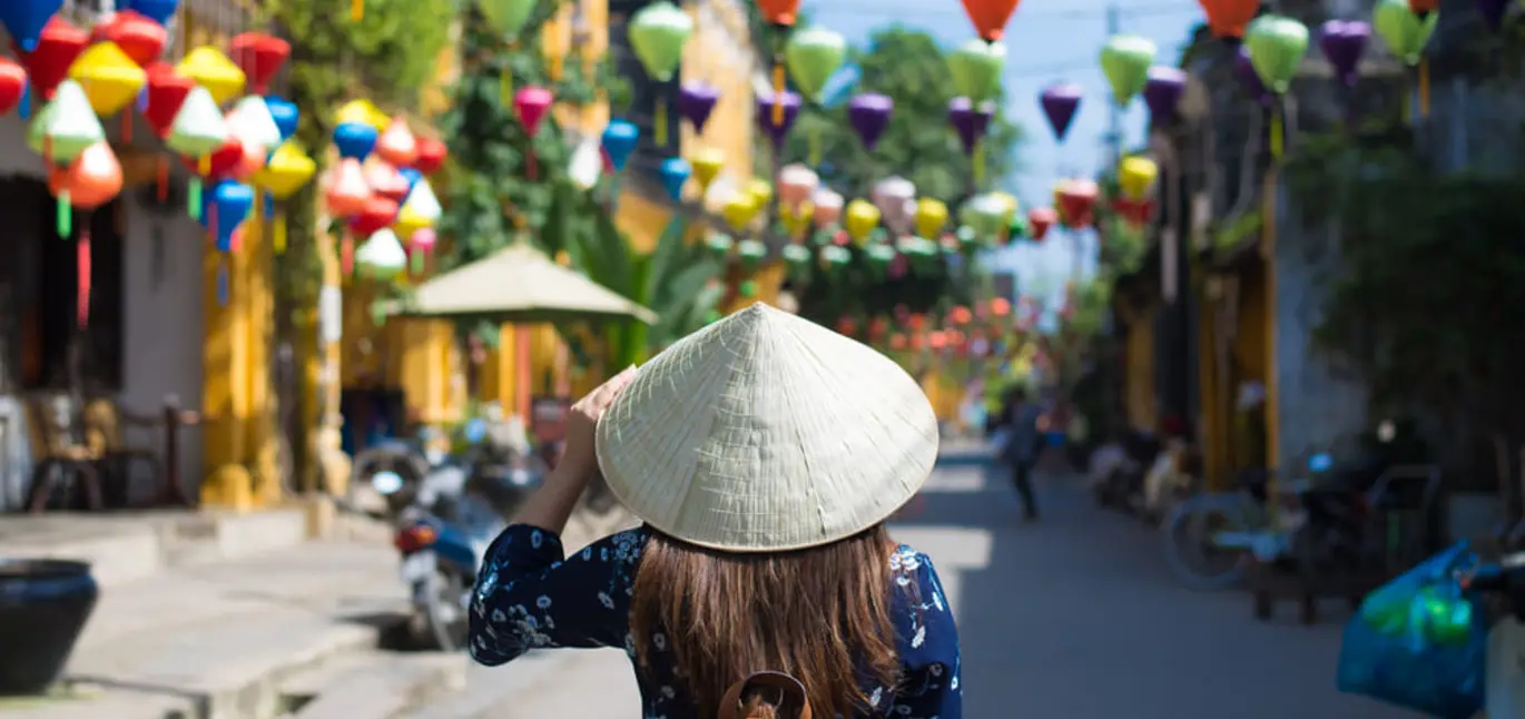 A woman wearing a traditional hat and exploring Vietnam