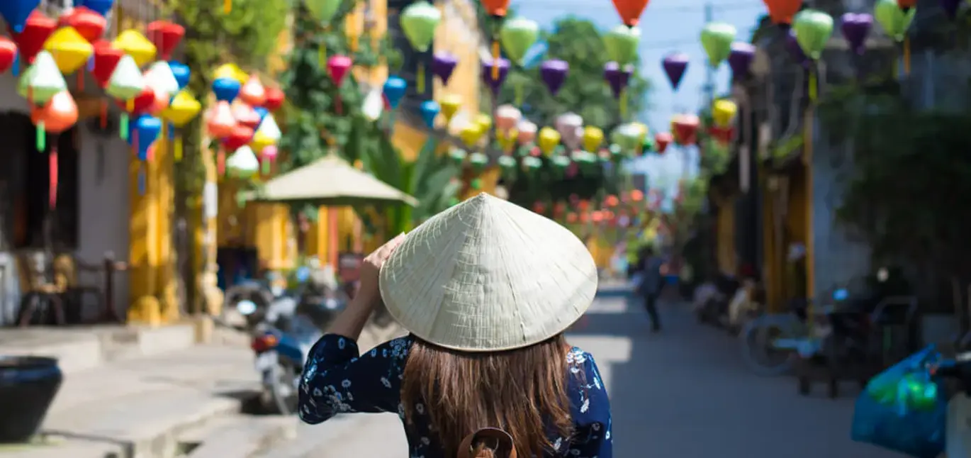 A woman wearing a traditional hat and exploring Vietnam