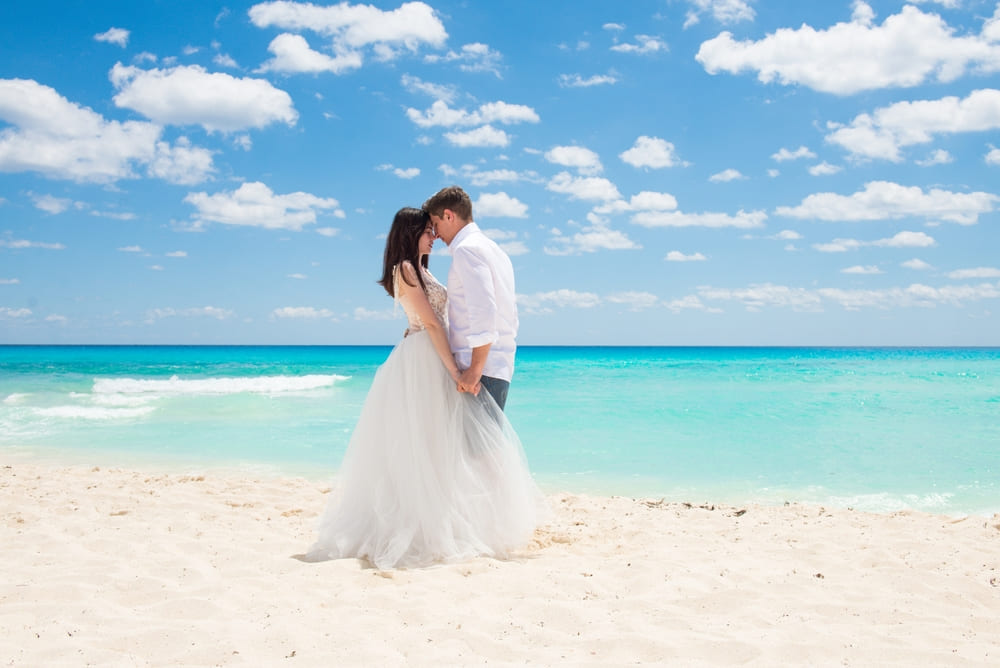 A newlywed couple holding hands on a beach