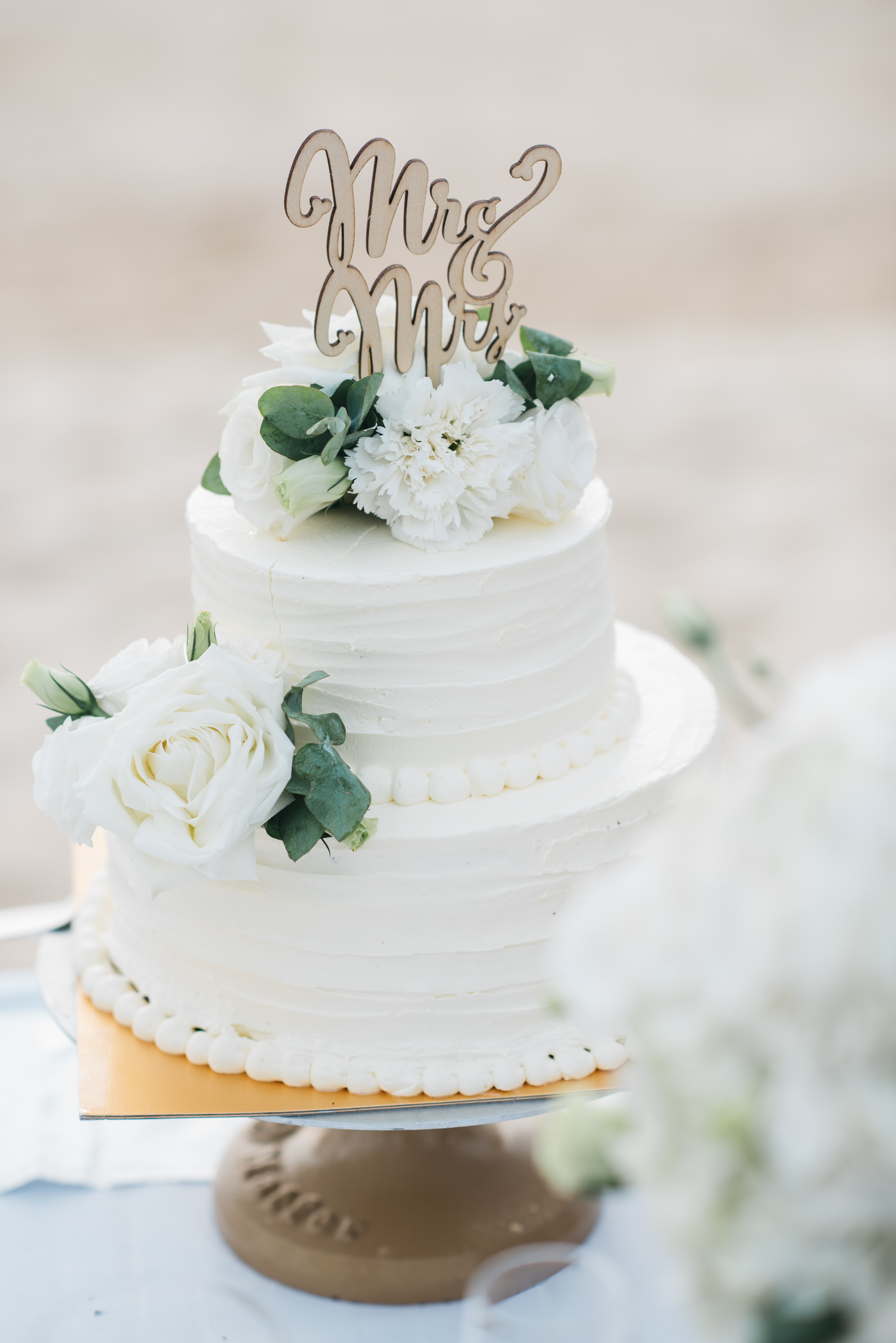 An elegant wedding cake with a wedding arch on a beach