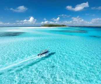 An aerial view of a boat zooming through the Maldivian sea 